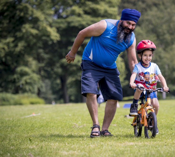 A man helps a young boy ride a bike.