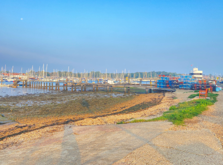 A view from the shore of a jetty, water and boats at Warsash Sailing Club.
